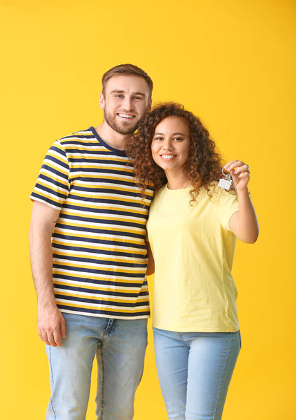 Joyeux jeune couple avec clé sur fond de couleur
 - Photo, image