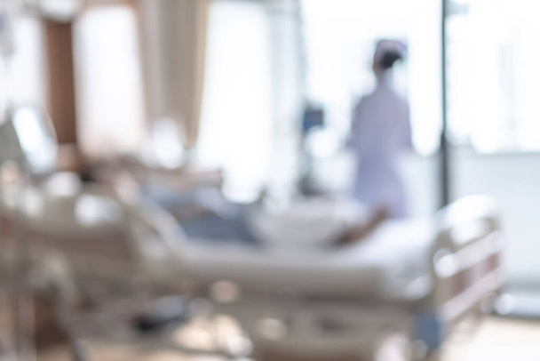 Sestra ošetřovatelka na nemocničním lůžku rozmazané pozadí, rozmazaný interiér bílý pokoj oddělení s nemocniční zdravotní péčí nebo léčba zotavení - Fotografie, Obrázek