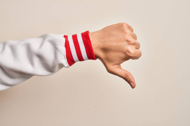 Mano de joven caucásico mostrando dedos sobre fondo blanco aislado haciendo pulgares hacia abajo gesto de rechazo, desaprobación aversión y signo negativo - Foto, Imagen