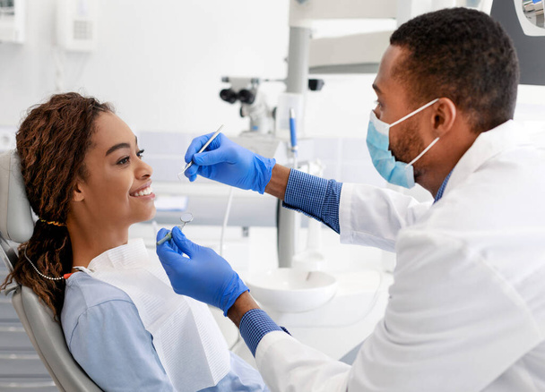 Afrikanerin lächelt Arzt auf Zahnarztstuhl an - Foto, Bild