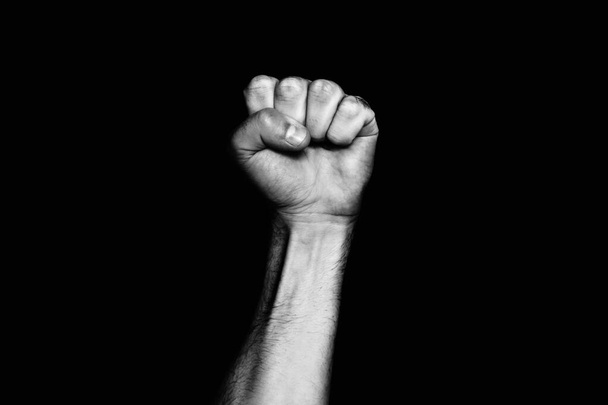 Male black fist on a black background. Aggressiveness, masculinity, the concept of challenge. - Photo, Image