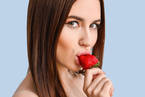 Sexy jovem mulher com morango no fundo de cor
 - Foto, Imagem