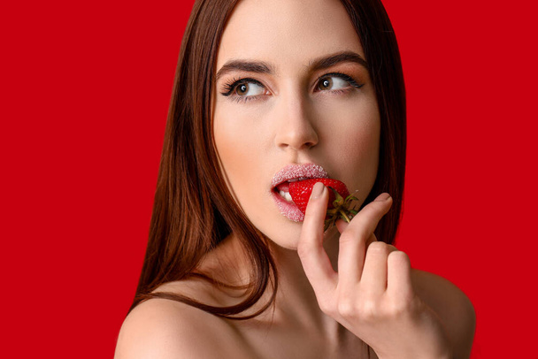 Sexy jonge vrouw met aardbei op kleur achtergrond - Foto, afbeelding