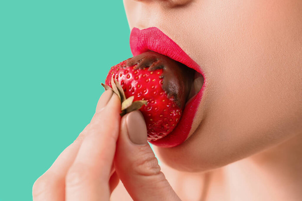 Sexy young woman with strawberry on color background, closeup - Foto, Imagen
