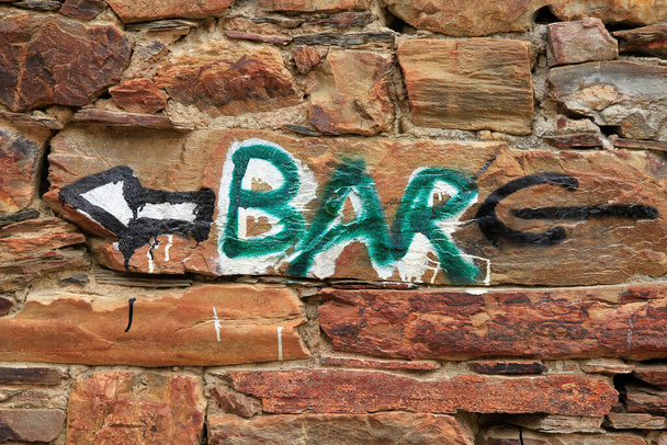 Indicador de barra ou sinalização com setas direcionais pintadas em uma parede de pedra na área rural
 - Foto, Imagem