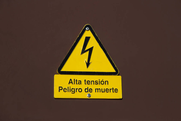 Signál nebezpečí úmrtí vysokým napětím ve španělštině v kovově hnědé stěně - Fotografie, Obrázek