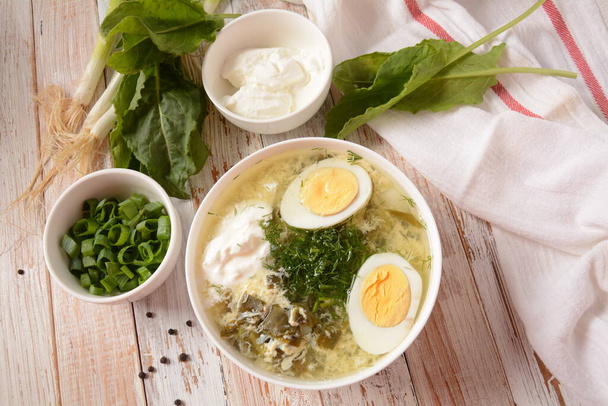Green sorrel and spinach soup with boiled egg, spring onion and sour cream on white wooden rustic table. Diet or healthy food concept - Foto, Imagen