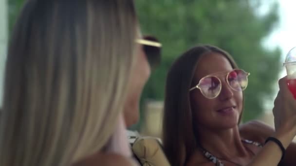 Mujeres felices en gafas de sol disfrutando de una bebida en la hermosa playa
 - Imágenes, Vídeo