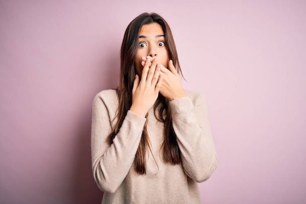 Young beautiful girl wearing casual turtleneck sweater standing over isolated pink background shocked covering mouth with hands for mistake. Secret concept. - Foto, immagini