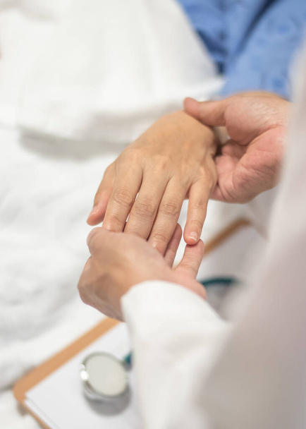 Ασθενής στο κρεβάτι με γιατρό που κρατιέται από το χέρι για νοσηλευτική περίθαλψη, ιατρική περίθαλψη, φροντιστής και νοσηλεύτρια - Φωτογραφία, εικόνα