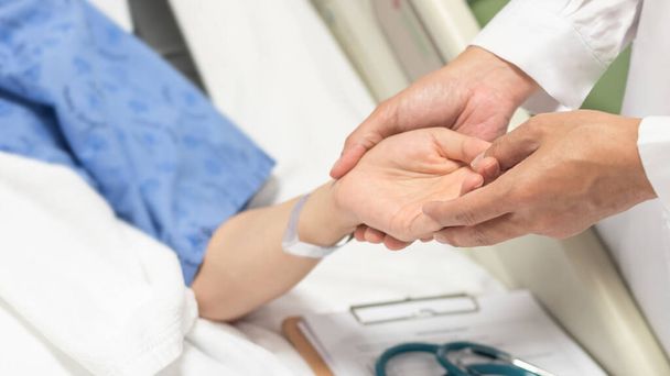 Patient au lit avec un médecin tenant la main pour les soins infirmiers, les soins médicaux, le soignant et le concept de soins de santé en salle d'hospitalisation - Photo, image