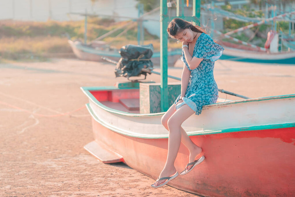Ασιάτισσα γυναίκα κάθεται σε μια βάρκα παραλία χαλαρώνοντας για το καλοκαίρι έννοια διακοπές στην παραλία. - Φωτογραφία, εικόνα