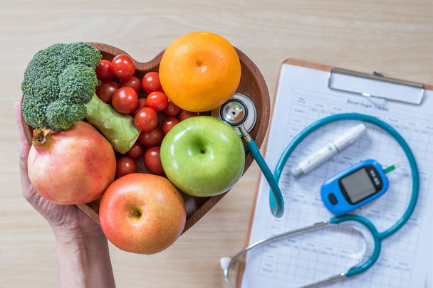 糖尿病モニター、コレステロール食と栄養士の心臓皿にきれいな果物と健康食品栄養コンセプトと糖尿病測定ツールキットと患者の血糖コントロールレコード - 写真・画像