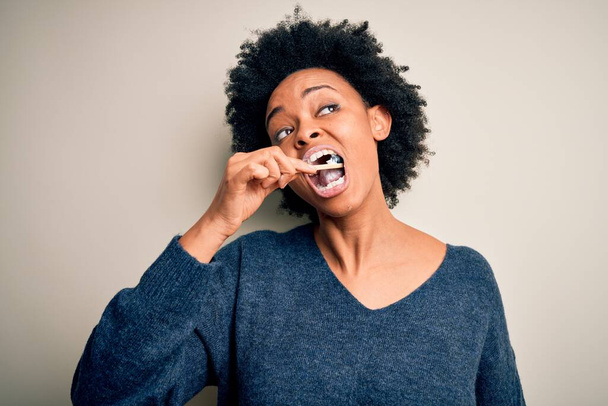 Mulher afro-americana escovando os dentes usando escova de dentes e pasta oral, limpando dentes e língua como rotina da manhã de cuidados de saúde saudável
 - Foto, Imagem