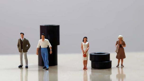 Двоє чоловіків мініатюри і дві жінки мініатюри стоять перед чорними блоками різного розміру
.  - Фото, зображення