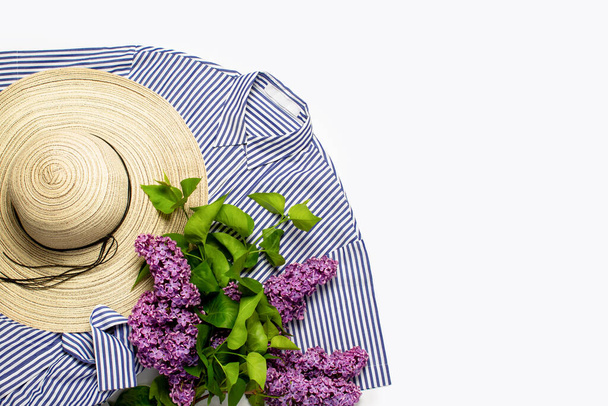 Cappello estivo femminile, vestito e rami di un lilla su uno sfondo bianco. Copia spazio, piatto, lay
. - Foto, immagini