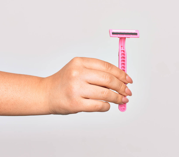 Hand of caucasian young woman holding pink razor over isolated white background - Fotó, kép