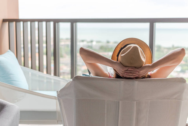 リラックスした健康的な生活ライフスタイルの夏休みフリーランスの女性は安心してリゾートホテルのバルコニーで快適な椅子で簡単に休息を取る心と自己の健康の質のバランス - 写真・画像