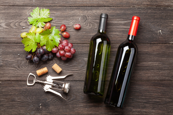 Erilaiset viinirypäleet, viinipullot ja korkkiruuvi puupöydällä. Huippunäkymä. Litteä - Valokuva, kuva