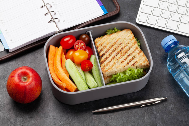 Υγιεινό κουτί φαγητού με σάντουιτς και λαχανικά στο τραπέζι του γραφείου - Φωτογραφία, εικόνα