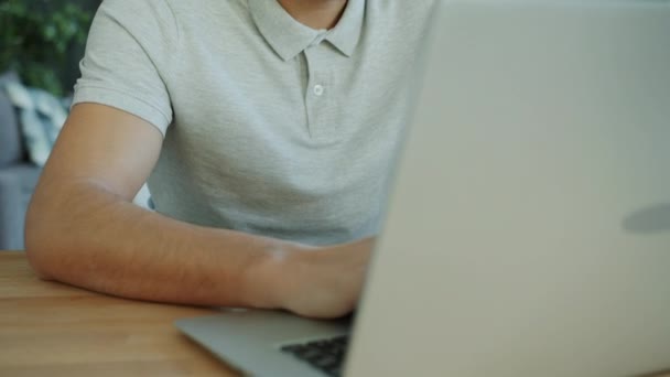 Tilt-up portrait of good-looking Arab man working with laptop computer in apartment typing - Video, Çekim