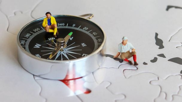 Dva miniaturní turisté sedící na kompasu.  - Fotografie, Obrázek