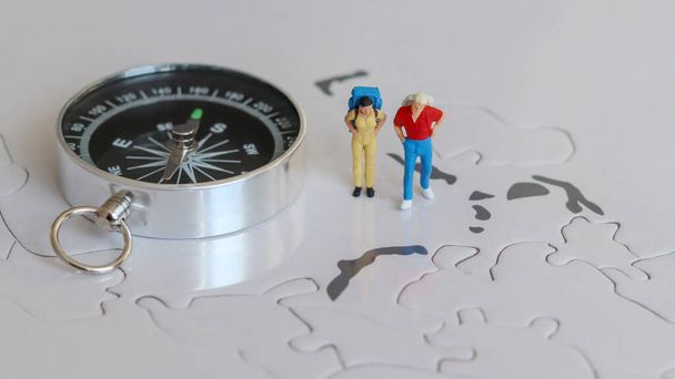Dva miniaturní turisté stojící vedle kompasu. - Fotografie, Obrázek