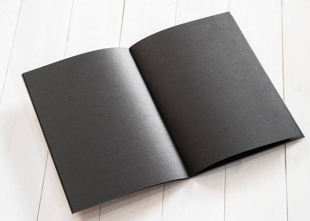 Plantilla de libro negro tamaño A4 en blanco maqueta con doble página abierta colocando en mesa de madera de superficie blanca cremosa - Foto, imagen