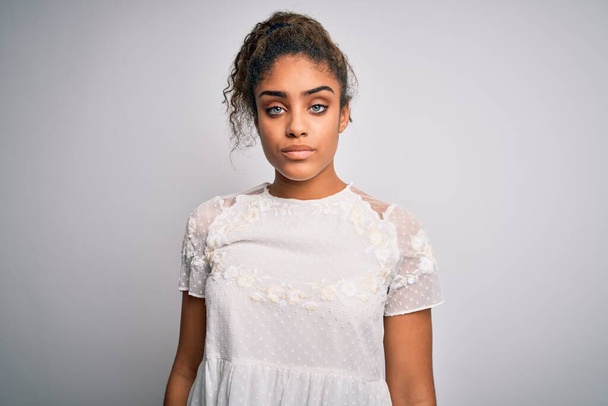 Jong mooi Afrikaans Amerikaans meisje draagt casual t-shirt staan over witte achtergrond Ontspannen met serieuze uitdrukking op gezicht. Eenvoudig en natuurlijk kijkend naar de camera. - Foto, afbeelding