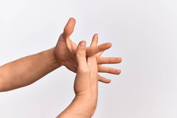 Χέρι του Καυκάσου νεαρός άνδρας δείχνει τα δάχτυλα πάνω από απομονωμένο λευκό φόντο που εκτείνεται με τα δάχτυλα συνυφασμένα, τα χέρια μαζί και τα δάχτυλα αλληλοσυνδέονται - Φωτογραφία, εικόνα