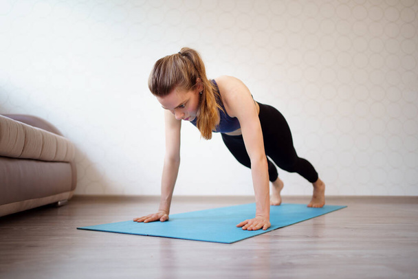 girl is engaged in sports at home online workouts on laptop. pushups and plank - Photo, Image