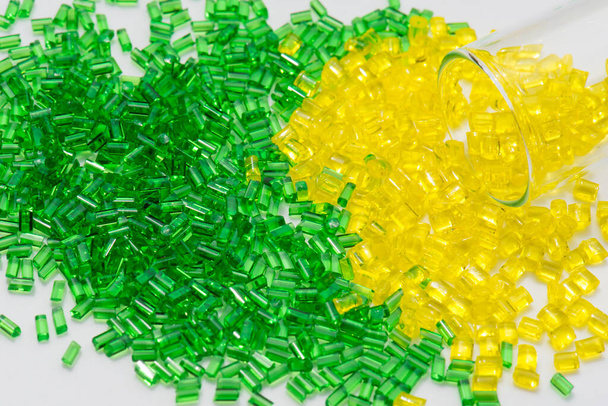 Polimero traslucido giallo e verde granula un bianco in laboratorio con vetro di prova - Foto, immagini