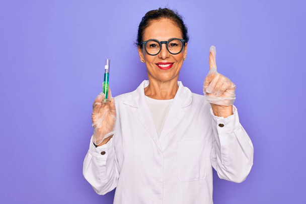 Középkorú vezető tudós nő visel laboratóriumi kabát gazdaság kutatási teszt cső meglepett egy ötlet vagy kérdés mutogató ujjal boldog arc, első számú - Fotó, kép