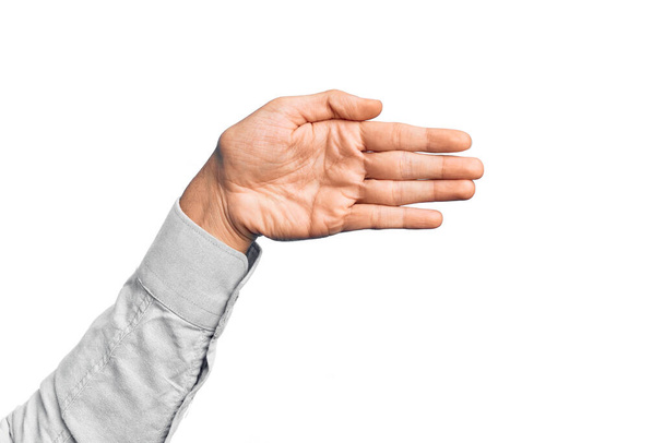 Main de jeune homme caucasien montrant les doigts sur fond blanc isolé étirant et atteignant avec la main ouverte pour la poignée de main, montrant la paume - Photo, image