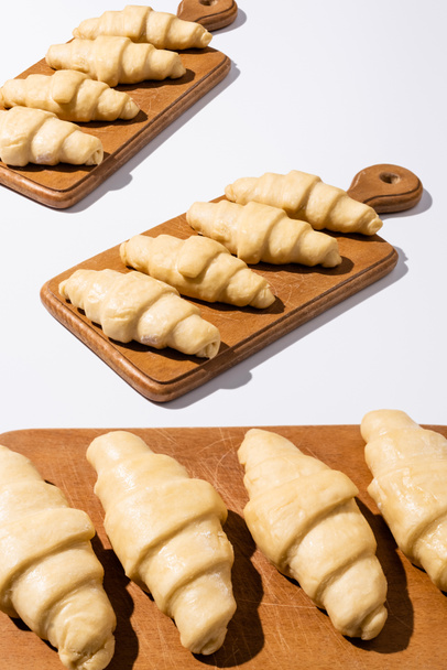 raw croissants on wooden cutting boards on white background - 写真・画像