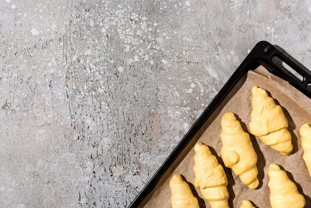 top view of uncooked croissants on baking tray on concrete grey surface - Фото, зображення