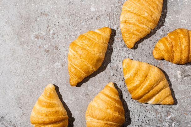 top view of fresh baked croissants on concrete grey surface - 写真・画像