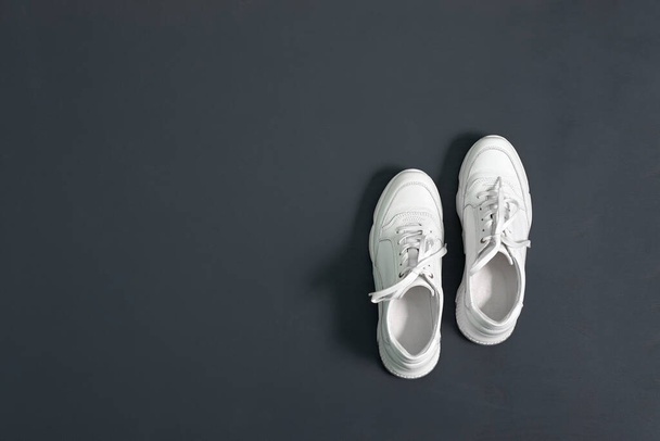 Zapatillas de deporte de cuero hipster blanco para mujer sobre fondo gris. Zapatillas con suela gruesa. Copiar espacio
. - Foto, imagen