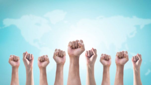 International human rights or labor day with Hands with clenched fist of people crowd (men and women) isolated on world map and sky background - Photo, Image
