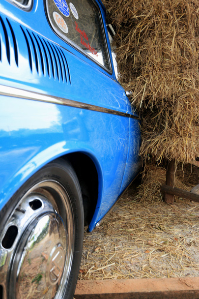 Part blue vintage car with a pile of straw. - Foto, afbeelding