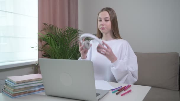 A young girl is trained at home online with headphones on her head. - Materiał filmowy, wideo
