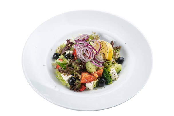 Greek salad on a white plate on a white isolated background. Cucumber, olives, peppers, oil, salad - Φωτογραφία, εικόνα