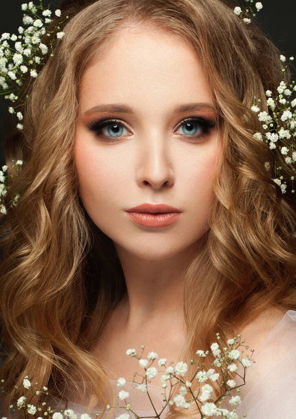 Beautiful young woman with long healthy curly hair and white flowers close up portrait - Foto, Imagem