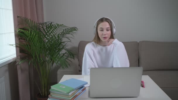 Girl is studying foreign language courses online with headphones. - Materiał filmowy, wideo