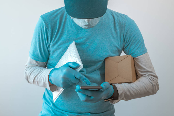 Delivery man with protective clothing using smartphone with protective gloves during viral infection pandemic, selective focus - Fotoğraf, Görsel