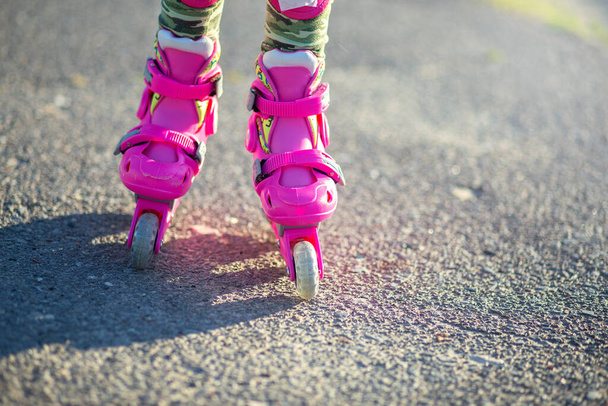 Παιδικά πόδια σε ροζ παιδικά ρολά γκρο πλαν. Πατίνια για αθλήματα εξωτερικού χώρου. Υγιεινός τρόπος ζωής - Φωτογραφία, εικόνα