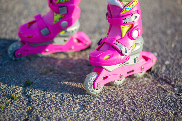 Los pies de los niños en los rodillos de los niños de color rosa de cerca. Patines para deportes al aire libre. Estilo de vida saludable bebé
 - Foto, imagen