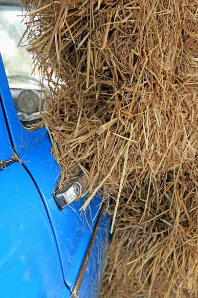 deel blauwe oldtimers met een stapel van strosaman yığını ile eski model araba parçası mavi. - Fotoğraf, Görsel