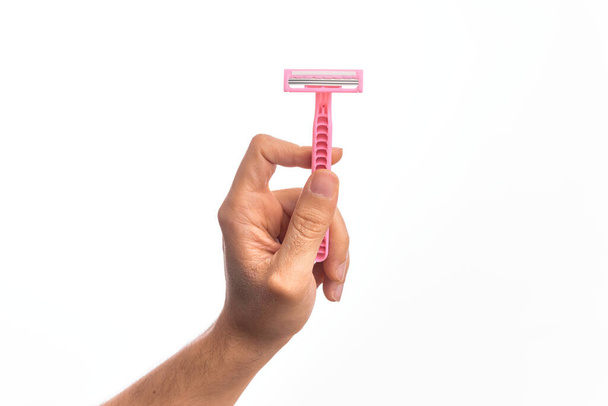 Hand of caucasian young man holding pink disposible razor over isolated white background - Foto, Imagem