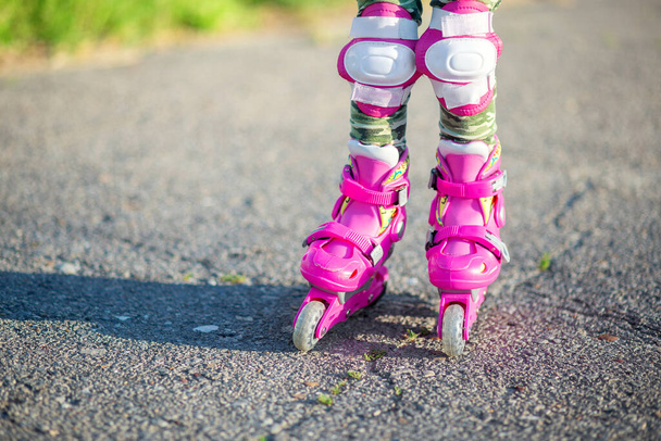 Los pies de los niños en los rodillos de los niños de color rosa de cerca. Patines para deportes al aire libre. Estilo de vida saludable bebé
 - Foto, Imagen